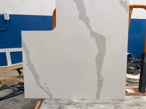 This quartz slab features a white base with bold gray veining, creating a modern and elegant look. The polished surface and intricate veining patterns add a luxurious touch, making it ideal for countertops, vanities, or accent pieces.