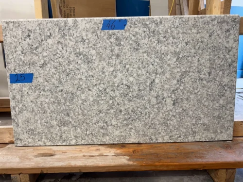 This quartz slab has a gray base with black and white speckled pattern, ideal for a timeless aesthetic. Its elegant design makes it perfect for small vanity tops, shower seats, window sills, door sills, or similar applications.